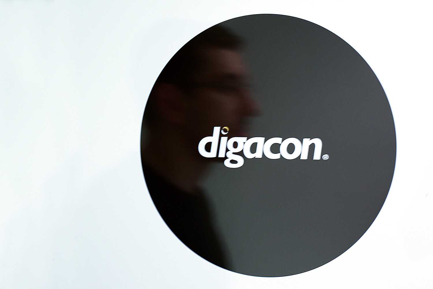Digacon logo on wall with man in reflection